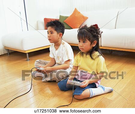 Stock Photo - A small boy playing video game along with his sister. Fotosearch