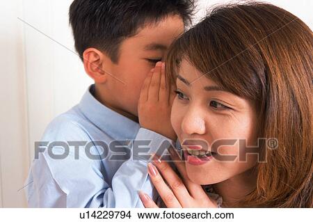 Picture - A small boy whispering to his mother. Fotosearch