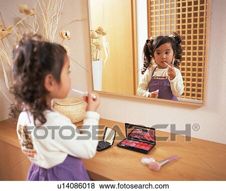 Stock Photo - A small girl applying lipstick. Fotosearch