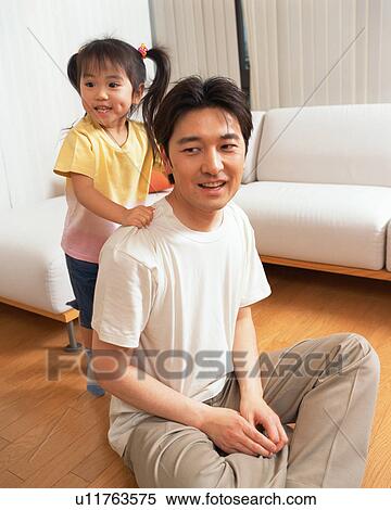 Stock Photography - A small girl standing behind her father. Fotosearch