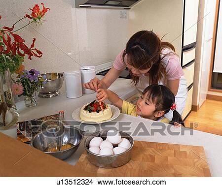 Picture - A young daughter decorating cake. Fotosearch