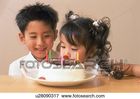 Stock Photo - Close up of a small boy and a small girl sitting near birthday cake. Fotosearch