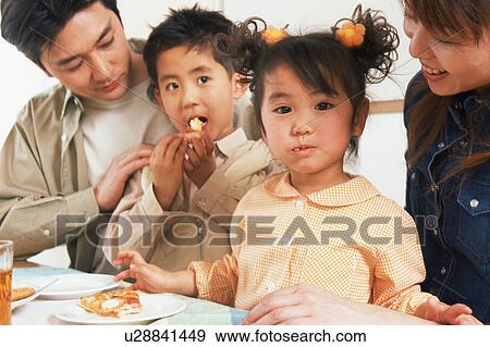 Stock Photo - Family eating pizza at table. Fotosearch