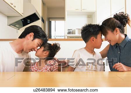 Picture - Side view of parents having eye contact with their two children. Fotosearch