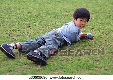 A boy lying in a park View Large Photo Image Stock Photograph - A boy lying in a park. Fotosearch