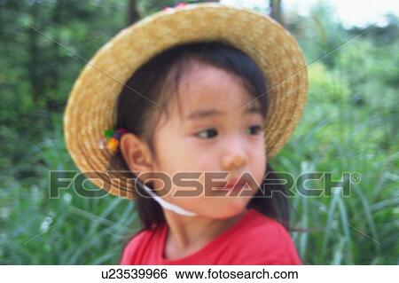 Stock Photograph - A girl wearing straw hat. Fotosearch