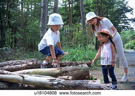 Stock Photo - Boy standing on logs and family watching. Fotosearch