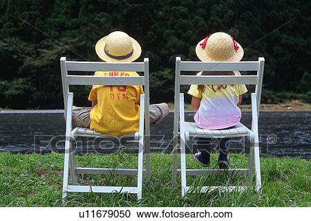 Stock Image - Children sitting at riverside. Fotosearch