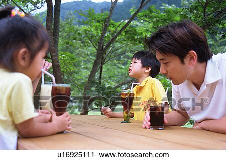 Stock Image - Family drinking juice at terrace. Fotosearch
