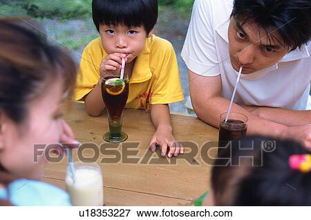 Stock Photo - Family drinking juice at terrace. Fotosearch