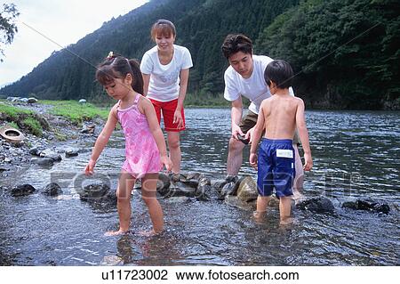 Stock Image - Family playing in a river. Fotosearch