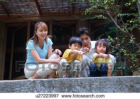 Stock Photo - Family sitting outside of log cabin. Fotosearch
