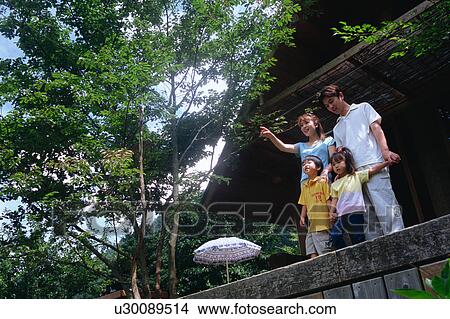Picture - Family standing outside of log cabin. Fotosearch