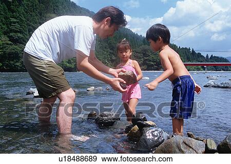 Stock Photo - Father and children playing in river. Fotosearch