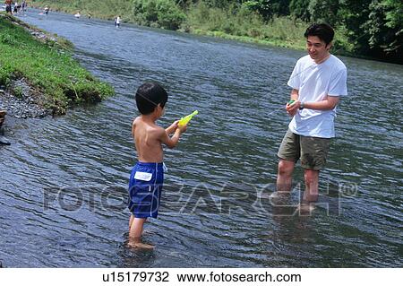 Stock Image - Father and son playing with squirt guns. Fotosearch