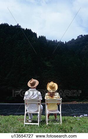 Stock Photo - Mid Adult Couple sitting at riverside. Fotosearch