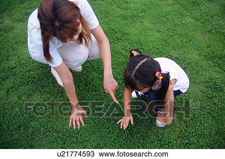 Mother and daughter looking at flower in a park View Large Photo Image Stock Image - Mother and daughter looking at flower in a park. Fotosearch