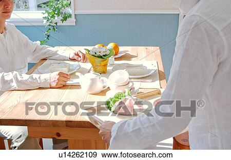 Stock Photo - A young couple at a table for breakfast. Fotosearch