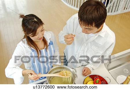 Stock Image - A young couple cooking in a kitchen. Fotosearch
