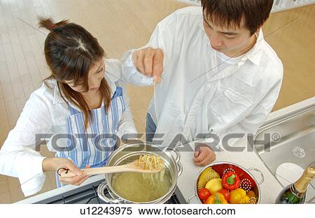 A young couple cooking in a kitchen View Large Photo Image Stock Photography - A young couple cooking in a kitchen. Fotosearch