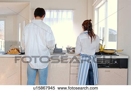 Stock Photography - A young couple cooking in a kitchen. Fotosearch