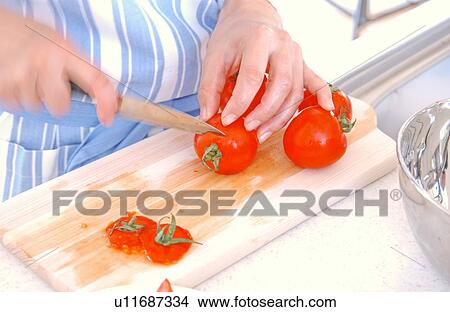 Picture - A young woman cutting tomatoes. Fotosearch