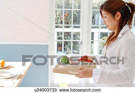 Stock Image - A young woman holding a tray. Fotosearch