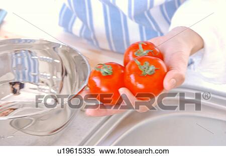 Stock Photography - A young woman holding tomatoes. Fotosearch