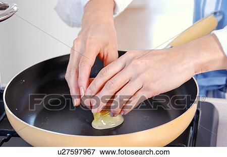 Stock Photo - Hands of a woman cooking an egg. Fotosearch