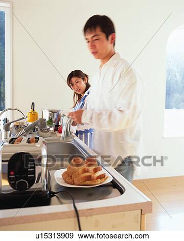 Stock Photo - Young couple cooking in a kitchen, blurred motion. Fotosearch