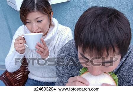 Picture - Young couple eating sandwiches. Fotosearch
