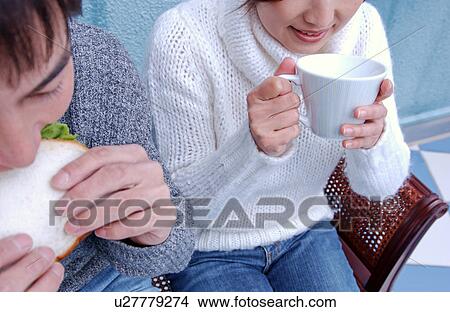 Picture - Young couple eating sandwiches. Fotosearch
