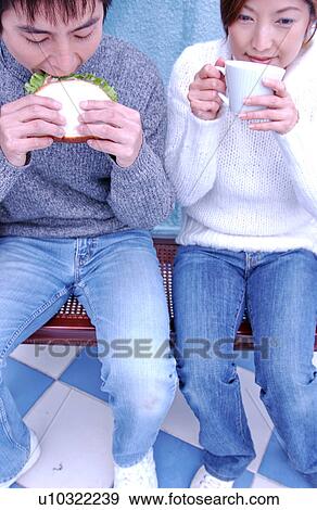 Stock Photo - Young couple eating sandwiches. Fotosearch