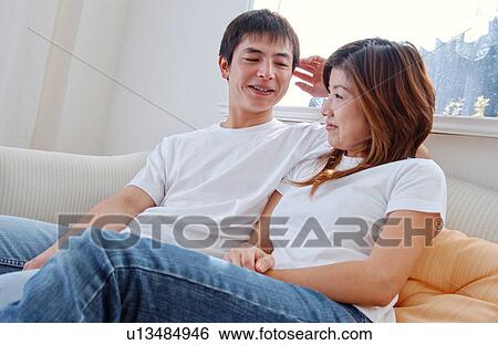 Stock Photograph - Young couple sitting on sofa and talking. Fotosearch