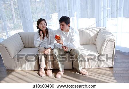 Young couple sitting on sofa View Large Photo Image Stock Image - Young couple sitting on sofa . Fotosearch
