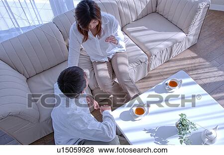 Young couple talking in a living room View Large Photo Image Stock Photo - Young couple talking in a living room. Fotosearch