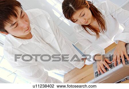 Young couple using computer at home View Large Photo Image Stock Image - Young couple using computer at home. Fotosearch