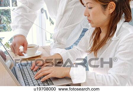 Stock Image - Young couple using computer at home. Fotosearch