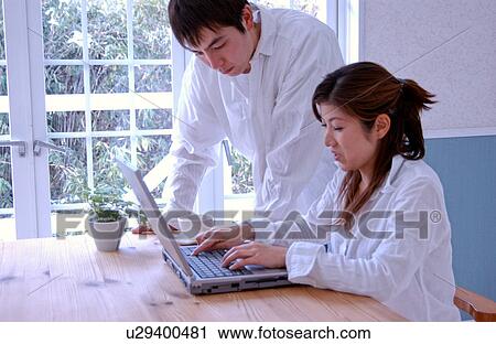 Stock Image - Young couple using computer at home. Fotosearch