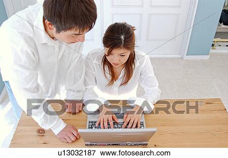 Stock Photo - Young couple using computer at home. Fotosearch