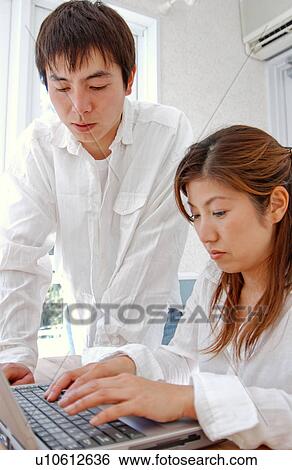 Stock Photograph - Young couple using computer at home. Fotosearch