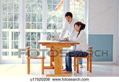 Stock Photograph - Young couple using computer at home. Fotosearch