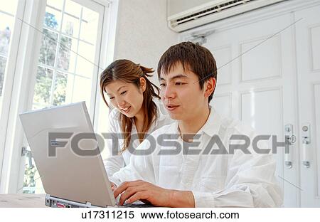 Stock Photography - Young couple using computer at home. Fotosearch