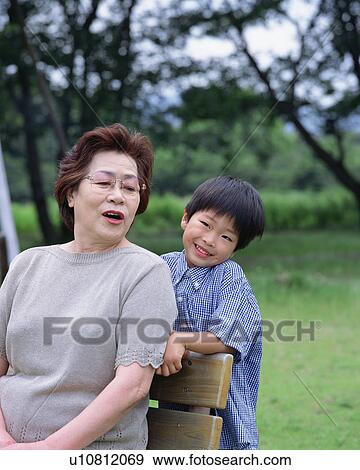 Stock Photo - A boy and a grand mother talking in a park. Fotosearch
