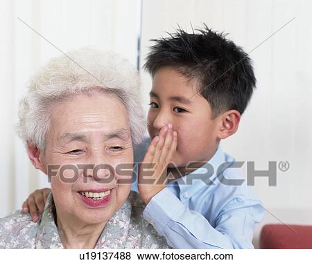 Stock Photo - A boy whispering to grand mother. Fotosearch