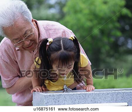 Stock Image - A girl drinking tap water in a park. Fotosearch