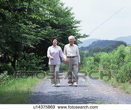 Stock Photo - A senior couple walking on a road. Fotosearch