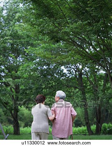 Stock Image - Senior couple walking in a park. Fotosearch