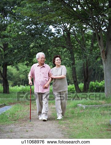 Senior couple walking in a park View Large Photo Image Stock Photograph - Senior couple walking in a park. Fotosearch