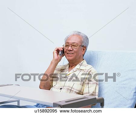 Stock Photography - A senior man in a bed talking with cellular phone. Fotosearch